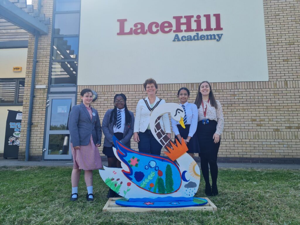 photo of swan sculpture and children outside a school with the mayor