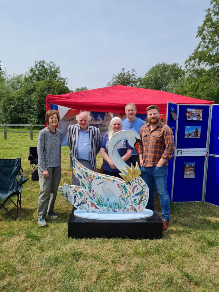 image shows a painted swan sculpture with the artist with the sponsors