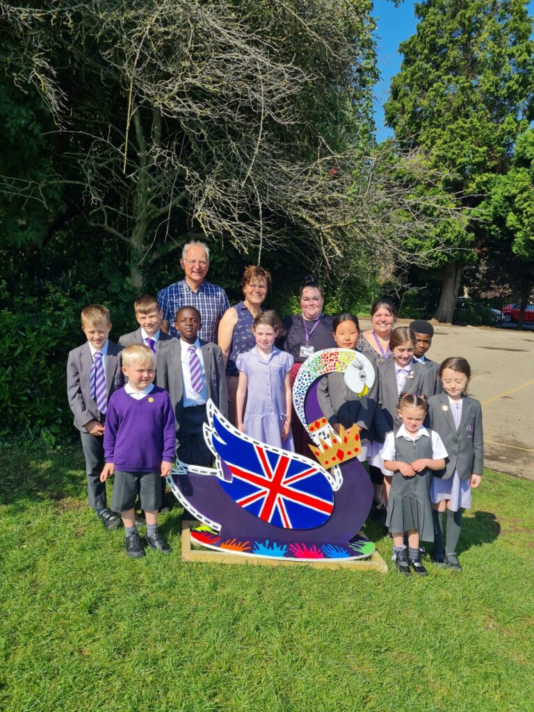 image shows a painted swan sculpture and school children