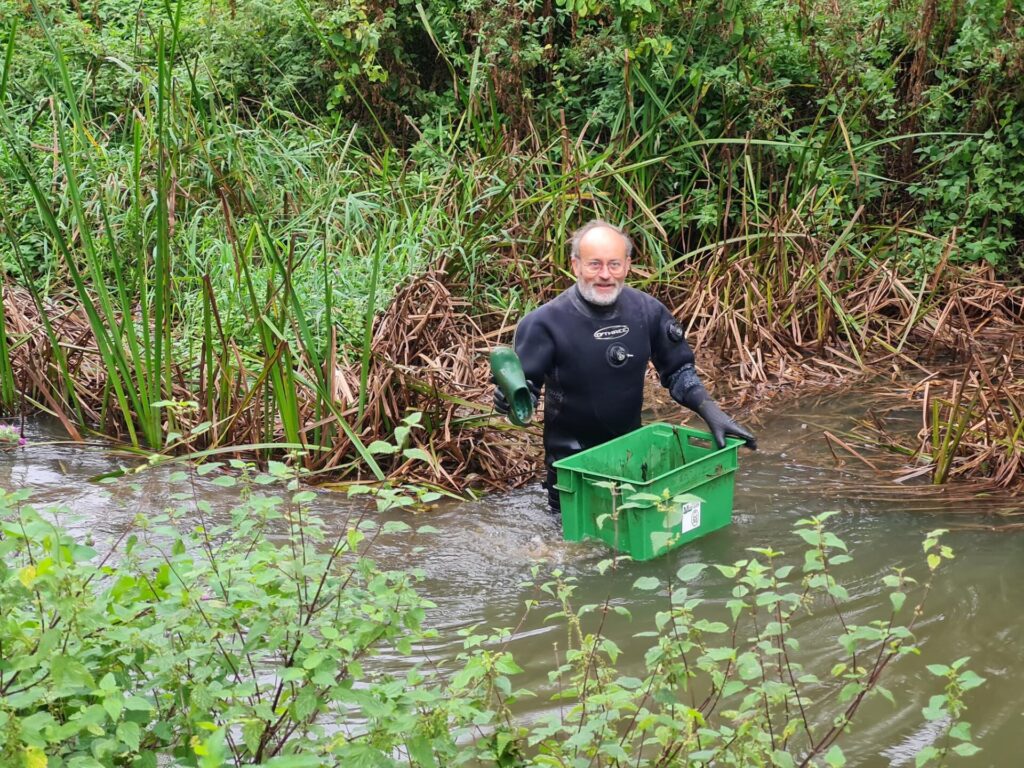 Diver holding up green show found in river 