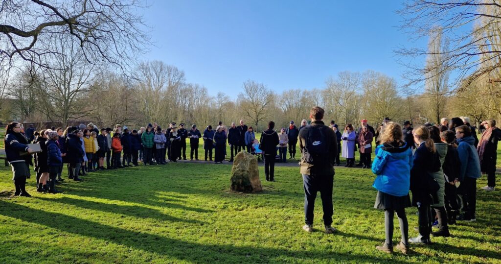 crowd of people surrounding holocaust memorial stone